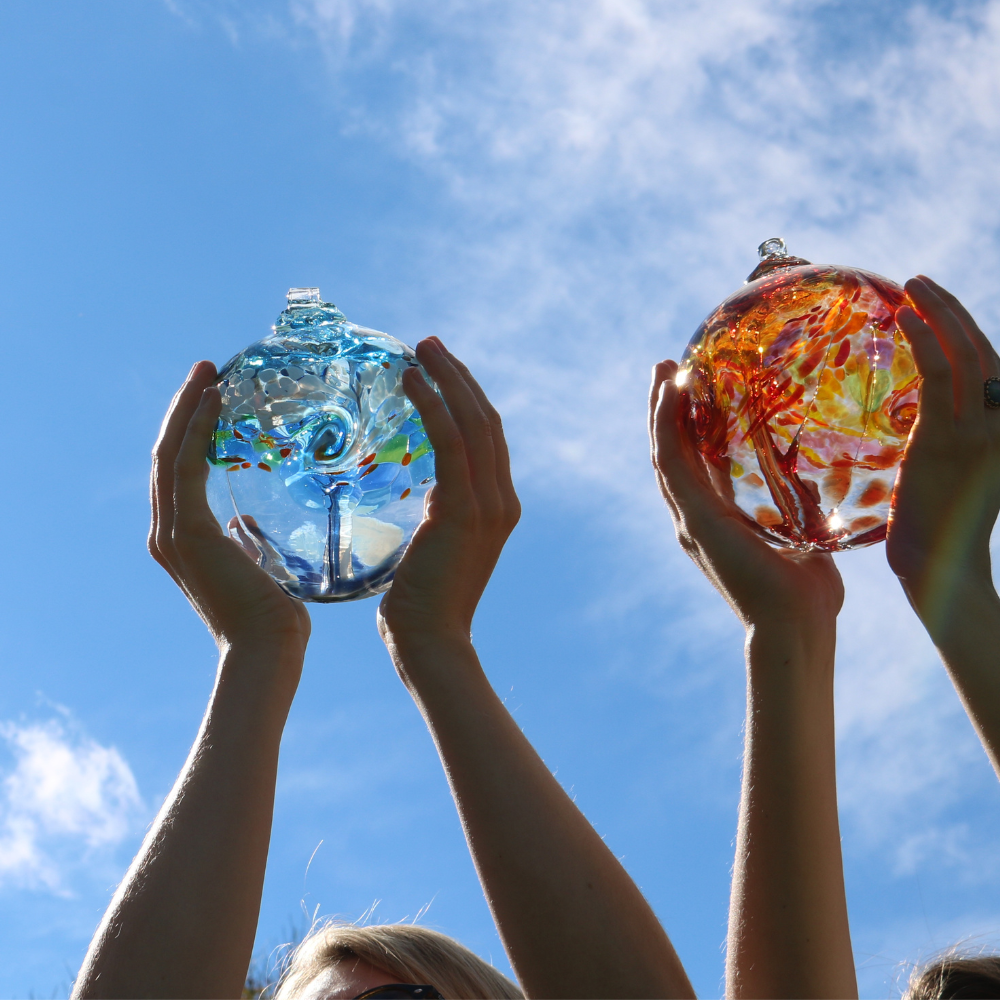 White and red orbs held in hands with a blue sky background.