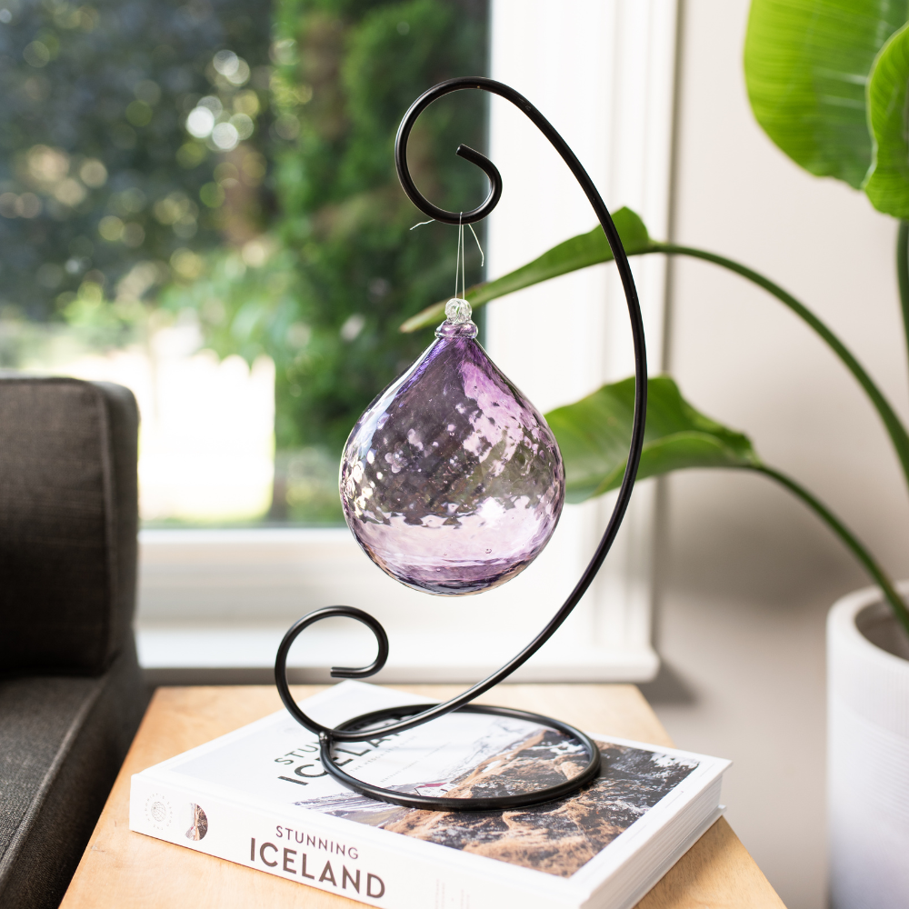 Majestic Twilight Radiance Drop on a Large Curved Single Ornament Stand. Displayed on book resting on an end table. 