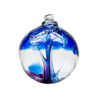 Clear glass orb with blue and purple glass pulled through the middle and purple and blue bits on top on a transparent background.