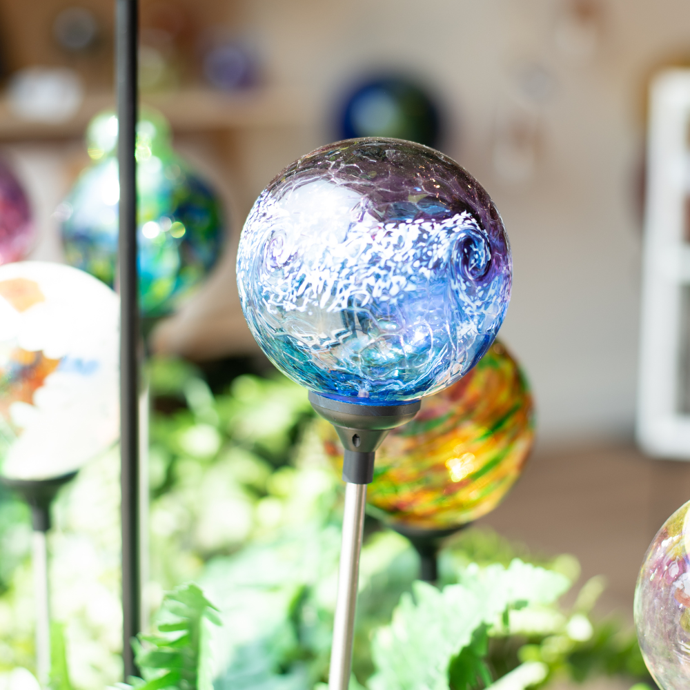 Purple/Blue Van Glow Solar Light amongst greenery. 