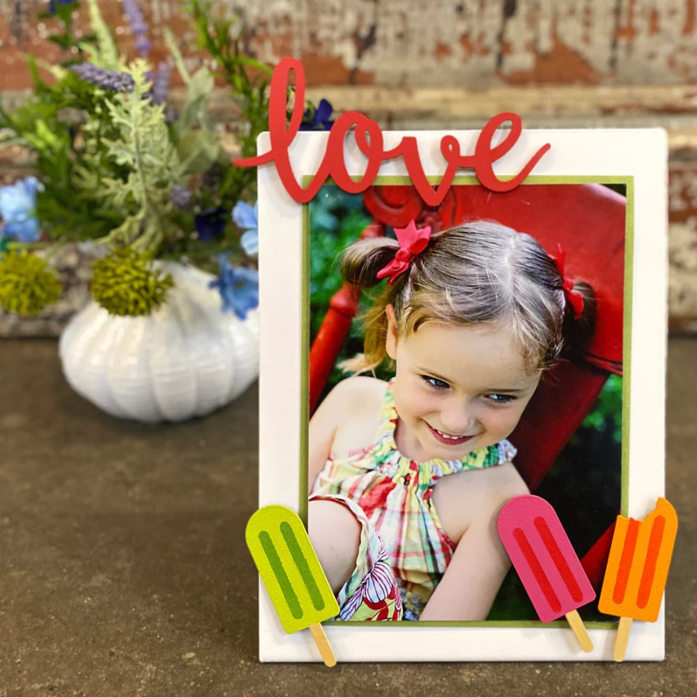 White memo board decorate with a photo of a girl and popsicle magnets and "Love" magnets. 