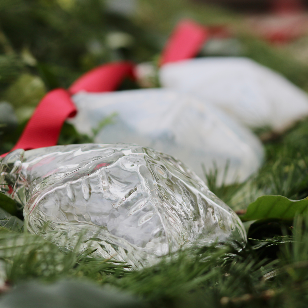 Clear, Milky and White snowflakes with a red ribbon on a bed of greens