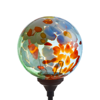 Glass orb with orange, white, yellow and green glass on the surface and a black clip in the bottom. On a transparent background. 